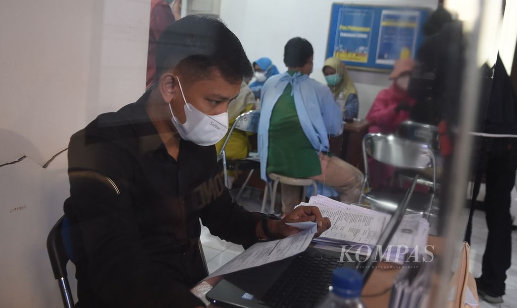 Petugas mengecek data warga yang akan mengikuti vaksinasi di Puskesmas Ketabang, Kota Surabaya, Jawa Timur, Sabtu (5/2/2022). Partisipasi warga untuk mendapatkan vaksinasi penguat meningkat sejalan dengan merebaknya kembali Covid-19 varian omicron. 