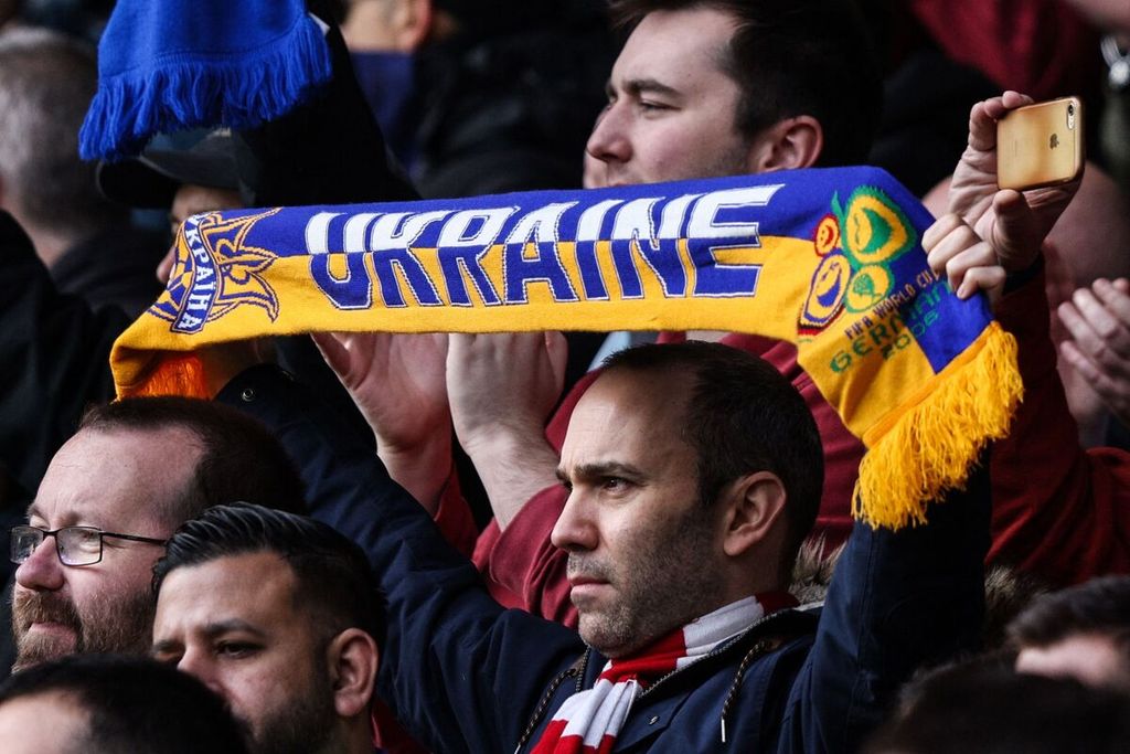 Seorang suporter membentangkan syal bertuliskan Ukraina untuk mendukung Ukraina yang menghadapi invasi Rusia di tengah pertandingan Liga Inggris antara Watford dan Arsenal di Stadion Vicarage Road, London, Inggris, Minggu (6/3/2022). 