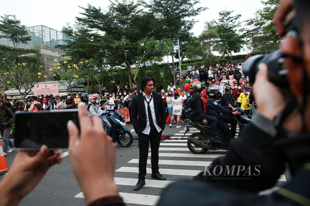 Seorang remaja dengan kostum seperti aktor Keanu Reeves dalam film <i>John Wick</i> berpose di <i>zebra cross</i> di Jalan Tanjung Karang di kawasan Dukuh Atas, Kecamatan Tanah Abang, Jakarta Pusat, Jumat (22/7/2022) sore. Kawasan yang viral dengan sebutan Citayam Fashion Week itu ramai dipadati anak muda yang membuat konten pribadi dan promosi produk.