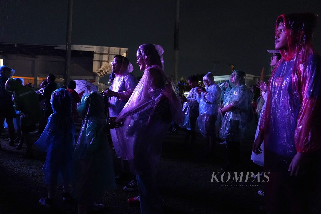 Penonton mengenakan ponco menikmati suguhan musik dalam Joyland Festival Jakarta 2023 di Lapangan Baseball, Kompleks Gelora Bung Karno, Senayan, Jakarta, Sabtu (25/11/2023). Sebanyak 48 penampil musik <i>manggung</i> di perhelatan festival musik Joyland 2023 yang berlangsung tiga hari tersebut. 
