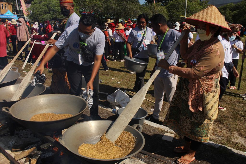 Para peserta <i>mangenta</i>, tradisi membuat ketan, di Kota Palangkaraya, Kalimantan Tengah, Minggu (22/5/2022), menyangrai padi ketan sebelum kemudian ditumbuk. <i>Mangenta </i>itu dikenalkan ke publik pada Festival Budaya Isen Mulang 2022.