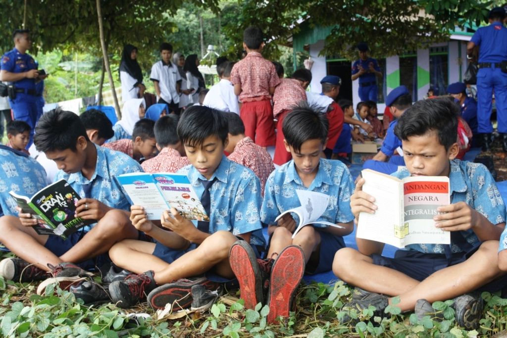 Anak-anak Kalimantan Tengah asyik membaca buku, Jumat (21/4/2017), yang didistribusikan oleh Polisi Air Polda Kalteng.