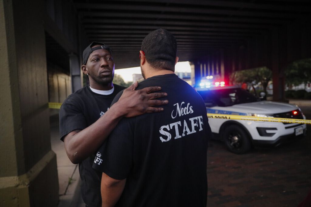 Para saksi saling menghibur di tempat penembakan massal, Minggu, 4 Agustus 2019, di Dayton, Ohio. Beberapa orang di Ohio telah tewas dalam penembakan massal kedua di AS dalam waktu kurang dari 24 jam dan tersangka penembak juga meninggal, kata polisi.