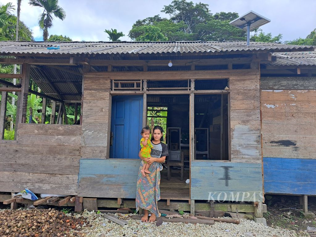 Wasnida Saogo menggendong putrinya, Riana, yang mengalami <i>stunting</i> atau tengkes di depan rumah mereka di Dusun Sinaka, Desa Sinaka, Kecamatan Pagai Selatan, Kepulauan Mentawai, Sumatera Barat, Sabtu (17/6/2023). Dusun Sinaka merupakan dusun dengan kasus <i>stunting</i> tertinggi dari 14 dusun di Desa Sinaka pada Mei 2023 dengan jumlah kasus 7 anak.