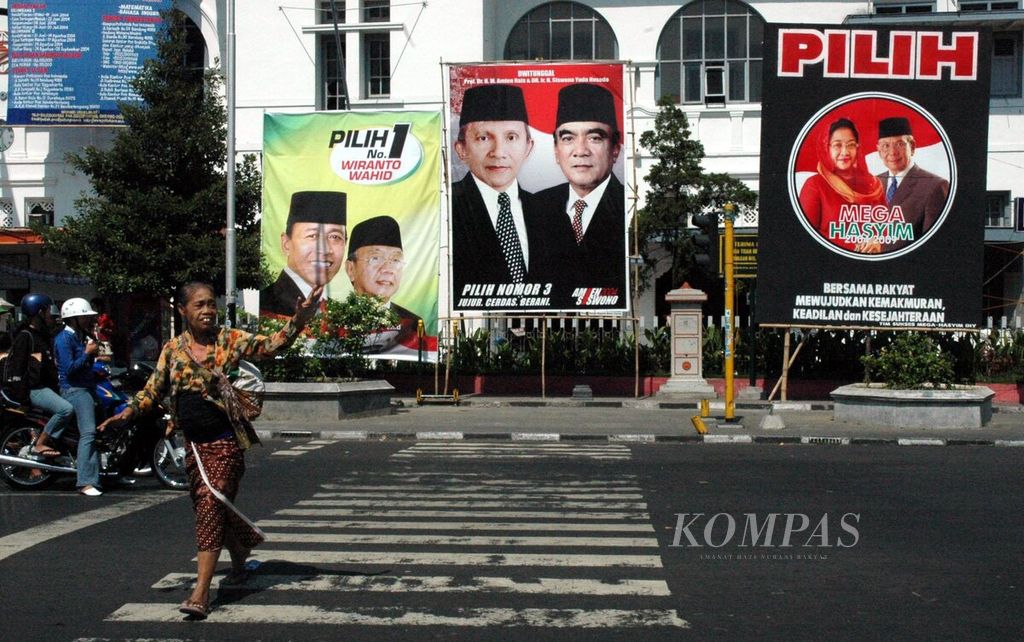 A mother crossed in front of the Yogyakarta Main Post Office on Tuesday (15/6/2004), with a background of large billboards offering candidates for the 2004-2009 Indonesian presidential election. These billboards now decorate strategic corners of the city of Yogyakarta, competing to be seen by many people.