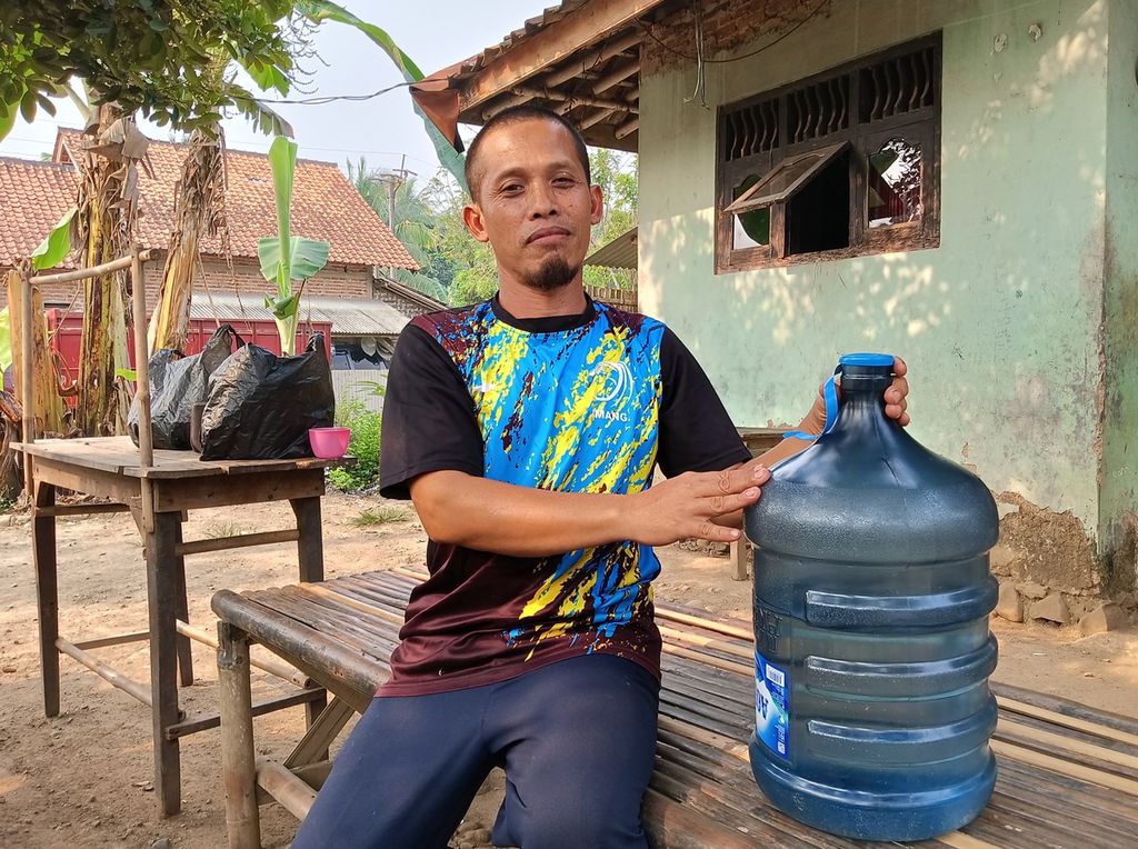 Ketua RT 001 Kampung Liud, Rosiman (47), menunjukkan air di ulang galon yang dibelinya untuk memenuhi kebutuhan harian, Senin (12/6/2023).