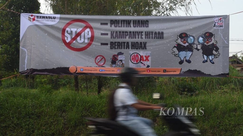 Pengendara melintas di sekitar spanduk yang dipasang Badan Pengawas Pemilihan Umum (Bawaslu) Jawa Timur di Jalan Raya Sukodono, Sidoarjo, Senin (11/12/2023). Spanduk tersebut berisi imbauan untuk stop politik uang, stop kampanye hitam, dan stop berita hoaks. 
