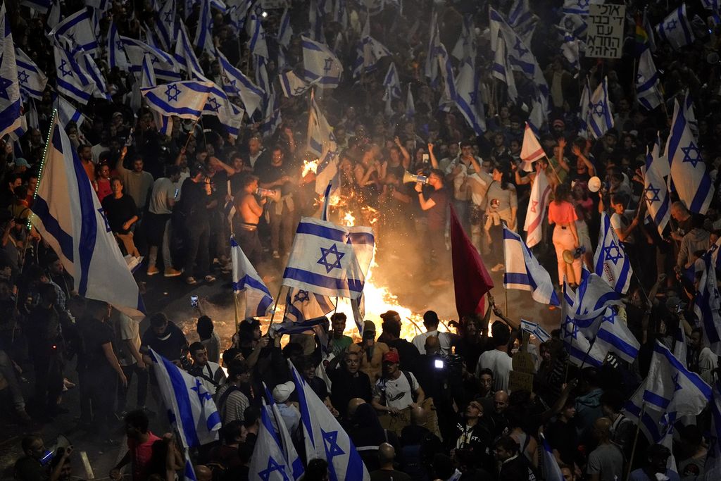 Warga Israel pengunjuk rasa penentang kebijakan Perdana Menteri Benjamin Netanyahu untuk mereformasi peradilan membakar benda-benda dan memblokade jalan raya dalam demonstrasi di Tel Aviv, Israel, 26 Maret 2023. 