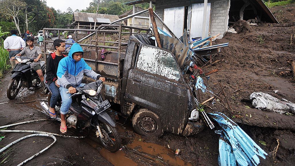 Sejumlah warga melintas di dekat rumah yang tersapu tanah longsor di Desa Songan, Kecamatan Kintamani, Kabupaten Bangli, Bali,  Jumat (10/2). Tanah longsor yang terjadi pada Kamis di tiga desa di Kintamani itu mengakibatkan 12 orang tewas, 5 orang luka-luka, dan 7 bangunan rusak.