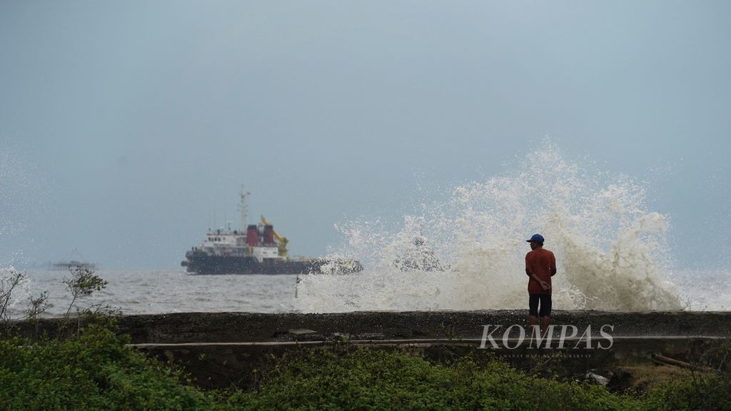 A man observes the waves hitting the sea wall at Marunda Beach, Cilincing, North Jakarta, Monday (26/12/2022). he Meteorology, Climatology and Geophysics Agency (BMKG) issued a weather forecast for the next seven days there will still be moderate, high to very high waves in a number of waters in Indonesia.