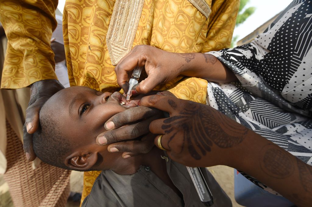 Pekerja kesehatan memberikan vaksin kepada seorang anak selama kampanye vaksinasi polio di Hotoro-Kudu, Distrik Nassarawa, Kano, Nigeria, Sabtu (22/4/2017). Organisasi Kesehatan Dunia (WHO) mengesahkan Benua Afrika "bebas dari virus polio liar" pada 25 Agustus 2020, empat tahun setelah kasus terakhir muncul di timur laut Nigeria, wilayah yang hancur akibat konflik melawan Boko Haram. 