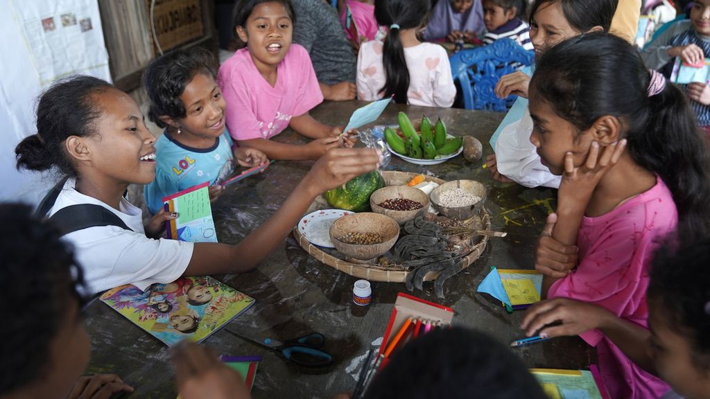 Anak-anak melihat dan memegang makanan lokal di Lakoat.Kujawas di Desa Taifob, Kecamatan Mollo Utara, Kabupaten Timor Tengah Selatan, NTT, Senin (7/8/2023). Anak-anak belajar menulis dan menggambar pangan lokal.
