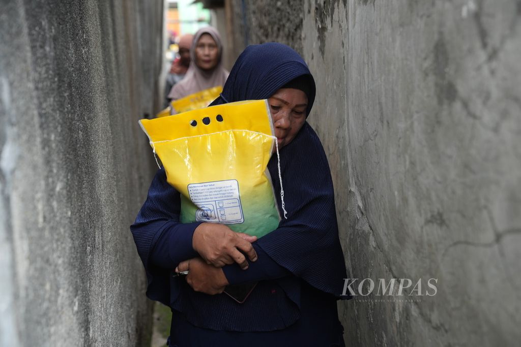 Warga melewati gang sempit setelah mendapatkan beras dalam operasi pasar beras stabilitas pasokan harga pangan di Kota Bekasi, Jawa Barat, Jumat (23/2/2024). Warga membeli beras yang dibanderol Rp 53.000 untuk kemasan 5 kilogram. 
