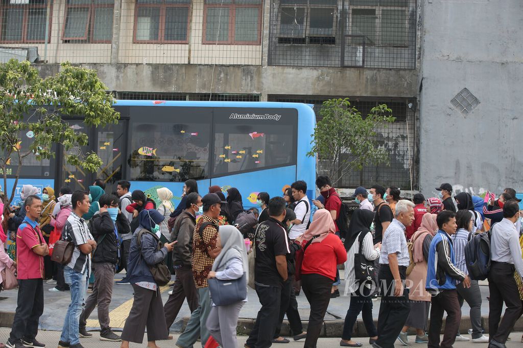 Warga antre di halte bus transjakarta koridor 13 di kawasan Puri Beta, Tangerang, Banten, Senin (13/3/2020) sekitar pukul 08.00. 