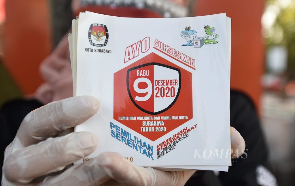 Anggota PPS, PPK, dan Panwascam Wonocolo membagikan stiker saat menyosialisasikan pemilihan wali kota 9 Desember di perempatan lampu merah Margorejo, Surabaya, Jawa Timur, Kamis (10/9/2020). 