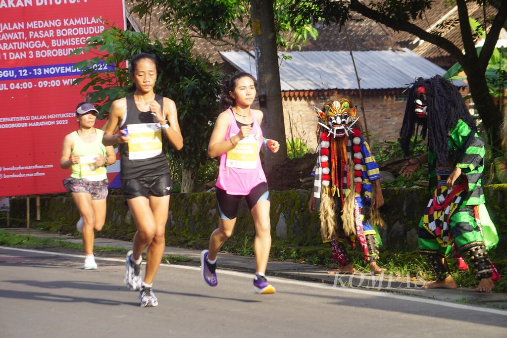 Para pelari putri Elite Race Borobudur Marathon 2022 Powered by Bank Jateng melintas di antara para penari Rampak Buto di Kawasan Candi Borobudur, Magelang, Jawa Tengah, Sabtu (12/11/2022).