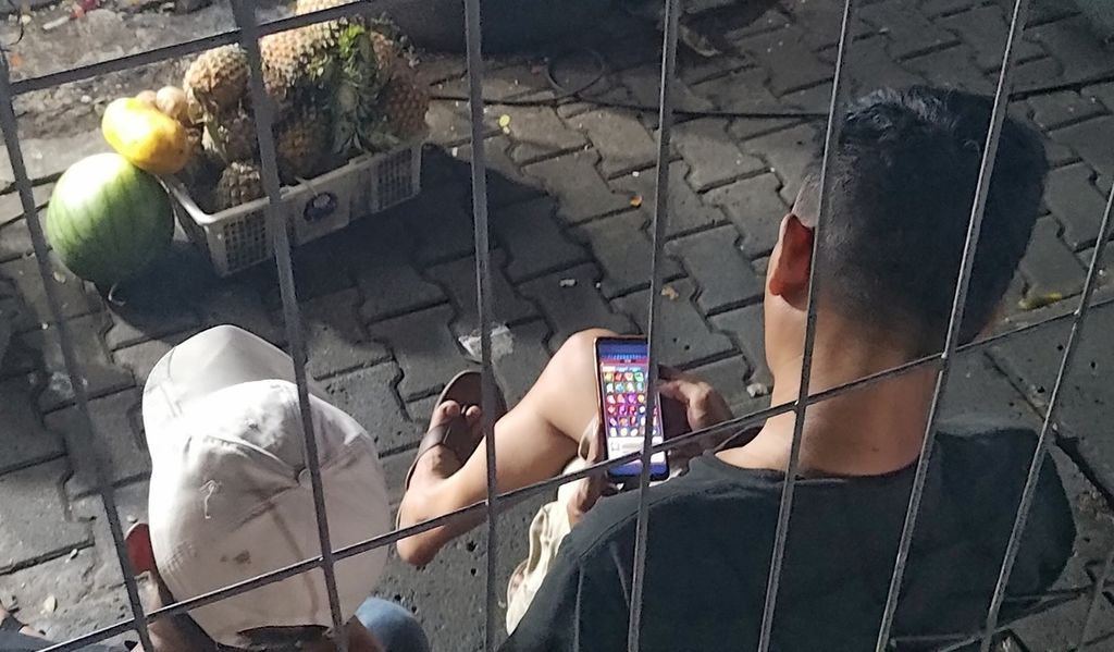 Seorang laki-laki tampak membuka situs judi slot lewat ponselnya ketika berada di daerah Jakarta Selatan, Jumat (24/11/2023).