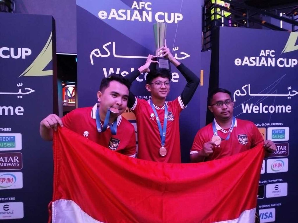 Akbar Paudie, Rizky Faidan, dan Elga Cahya Putra (dari kiri-kanan), skuad Timnas e-Sport Indonesia, berfoto dengan trofi juara Piala Asia Elektronik 2023 di Virtuocity eSports Arena, Doha, Qatar, Senin (5/2/2024). Mereka menumbangkan Jepang pada partai puncak.