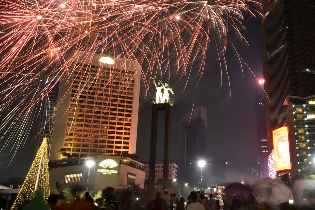 Sejumlah warga menyaksikan pertunjukan kembang api di Bundaran HI, Jakarta Pusat, Minggu (1/1/2023). 