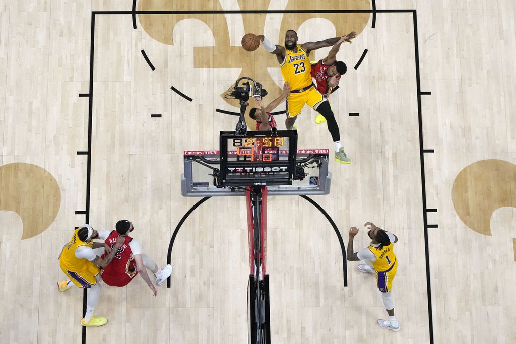 Pebasket Los Angeles Lakers, LeBron James, melempar bola di antara pebasket New Orleans, Trey Murphy III dan CJ McCollum, dalam pertandingan babak play-in di Smoothie KIng Center, New Orleans, Rabu (17/4/2024) WIB. 