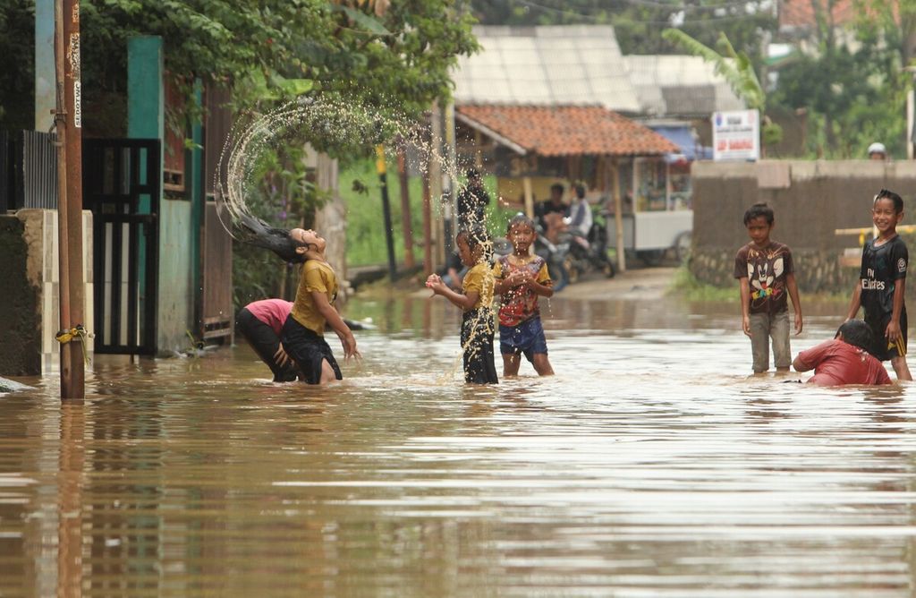 Anak-anak bermain di Jalan Andir-Katapang, Kabupaten Bandung, Jawa Barat, yang tergenang banjir, Kamis (11/11/2021). Banjir di kawasan itu berangsur surut. Namun, warga masih mewaspadai banjir kembali meninggi karena musim hujan diprediksi terjadi hingga awal tahun depan. 