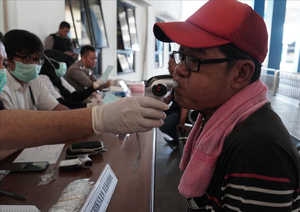 Seorang sopir bus meniup alat pengukur kandungan alkohol di Terminal Tirtonadi, solo, Jawa Tengah, Rabu (2/5/2019). Puluhan sopir bus menjalani pemeriksaan kesehatan dan tes urine di Terminal Tirtonadi.