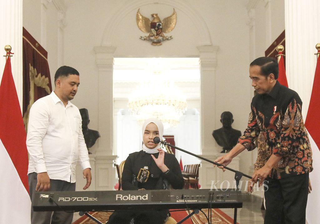 Presiden Joko Widodo membetulkan posisi mikrofon penyanyi Putri Ariani sebelum bernyanyi di Istana Merdeka, Jakarta, Rabu (14/6/2023). 