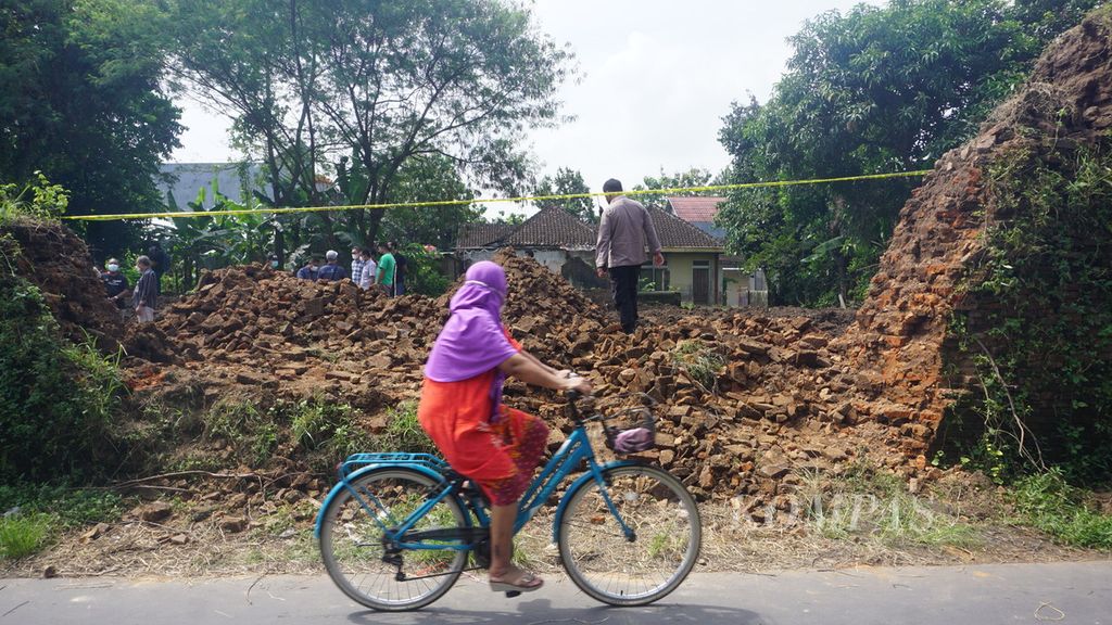 Warga melintas di depan Benteng Keraton Kartasura yang jebol di Kabupaten Sukoharjo, Jawa Tengah, Sabtu (23/4/2022). Benteng itu dijebol oleh pemilik lahan yang tengah membersihkan kompleks keraton tersebut. Adapun lahan yang dimiliki berada di balik tembok itu. Benteng dijebol untuk memasukkan alat berat.