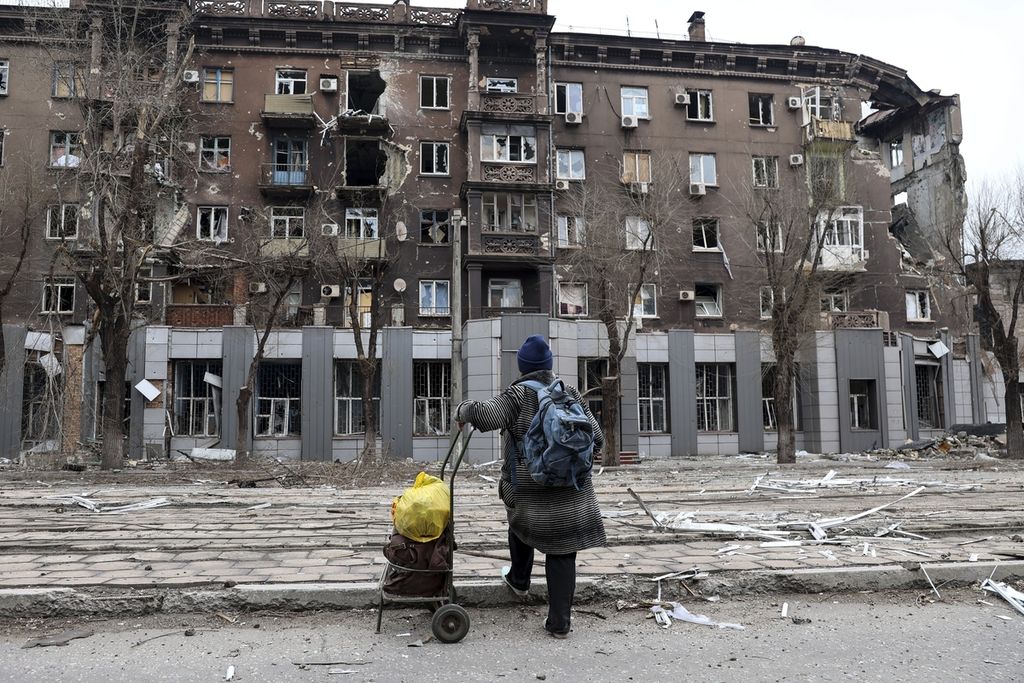 Seorang warga setempat mengamati gedung apartemen yang rusak akibat pertempuran sengit di dekat Pabrik Metalurgi Baja dan Besi Illich di area yang dikontrol Rusia di Mariupol, Ukraina, 16 April 2022. 