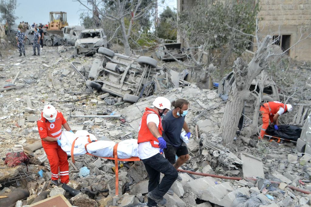 Petugas Palang Merah Lebanon mengangkut jenazah yang ditemukan di reruntuhan di lokasi serangan udara Israel yang menargetkan Desa Aito di Lebanon utara, Senin (14/10/2024).