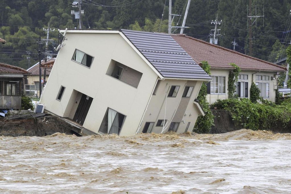 Bantaran Sungai Suzu terkikis akibat sungai meluap hingga menyebabkan sebuah rumah miring di Suzu, Jepang, Minggu (22/9/2024). 