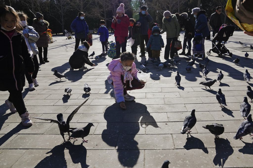 Seorang anak memberi makan merpati di sebuah taman di Beijing, Cina, 13 Januari 2022. Jumlah kelahiran bayi di China terus menurun sampai pada angka terendah dalam satu dekade pada tahun lalu.  