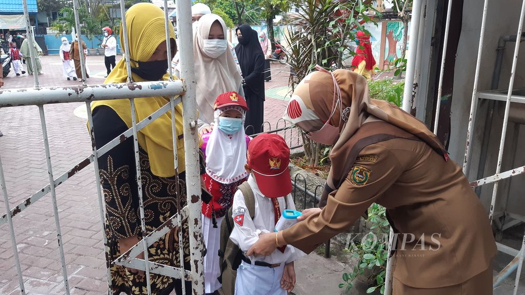 Guru memeriksa suhu tubuh siswa yang akan mengikuti pembelajaran tatap muka (PTM) di SD Negeri Pasar Lama 3, Kota Banjarmasin, Kalimantan Selatan, Senin (12/7/2021). 