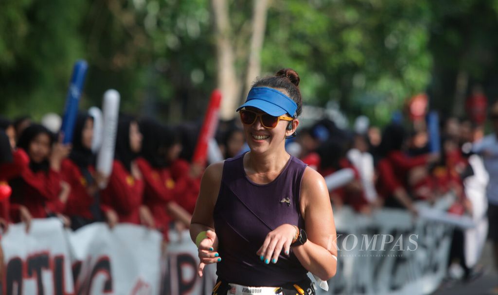 Peserta lari Tilik Candi memberikan senyumannya bagi para tim yel-yel yang memberi semangat menjelang garis finis pada Borobudur Marathon 2022 Powered by Bank Jateng di Taman Lumbini, kawasan Candi Borobudur, Jawa Tengah, Minggu (13/11/2022).