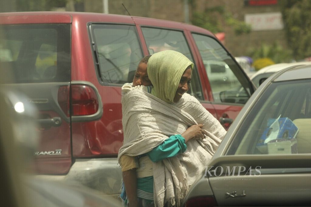 Pengemis sambil menggendong anaknya mengemis di salah satu ruas jalan utama di Addis Ababa, Etiopia. Pemerintah Etiopia terus berupaya menurunkan angka kemiskinan. Foto diambil pertengahan April 2019.