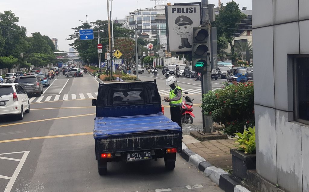 Seorang polisi menindak pelanggar aturan ganjil genap di Jalan Salemba Raya, Jakarta Pusat, Senin (13/6/2022).