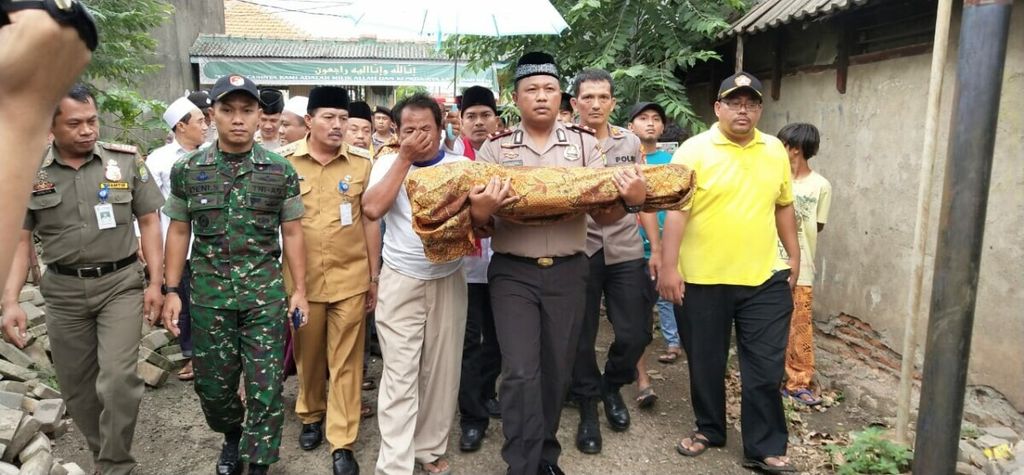 Kepala Polsek Jatiuwung Komisaris Eliantoro Jalmaf membawa jenazah bayi QLR (1,5), korban penganiayaan oleh ibu kandungnya, Rs (28), di Sangiang Jaya, Kecamatan Jatiuwung, Kota Tangerang, ke tempat pemakaman, Senin (21/1/2019).