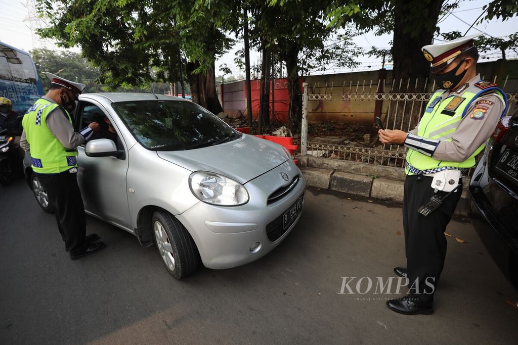 Anggota Direktorat Lalu Lintas Polda Metro Jaya memotret mobil yang melanggar aturan ganjil genap di Simpang Cawang, Jakarta Timur, Senin (10/8/2020).
