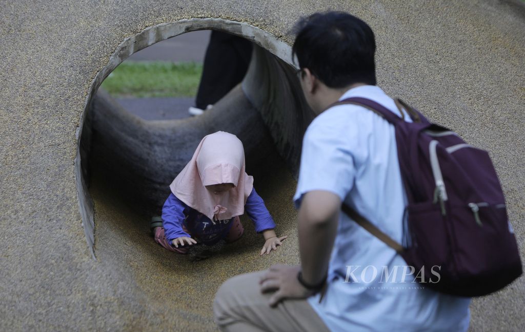 Seroang ayah menemani anaknya bermain di terowongan taman bermain Tebet Eco Park, Jakarta Selatan, Kamis (21/3/2024). 