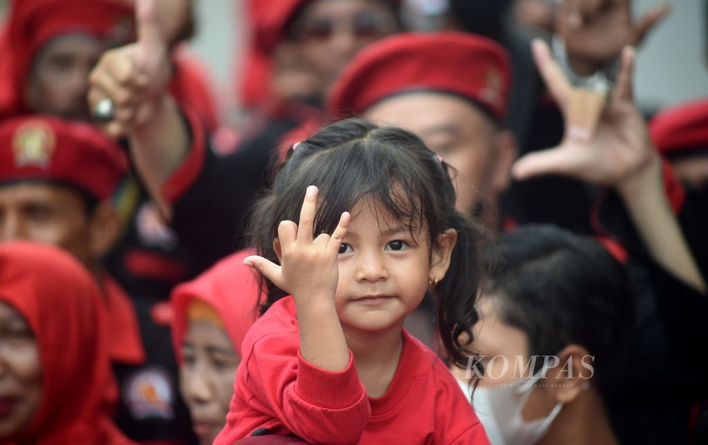 Seorang anak ikut orangtuanya menyambut kedatangan calon presiden dari PDI-P, Ganjar Pranowo, di Posko Gotong Royong, Jalan Pandegiling, Surabaya, Jawa Timur, Sabtu (6/5/2023). 