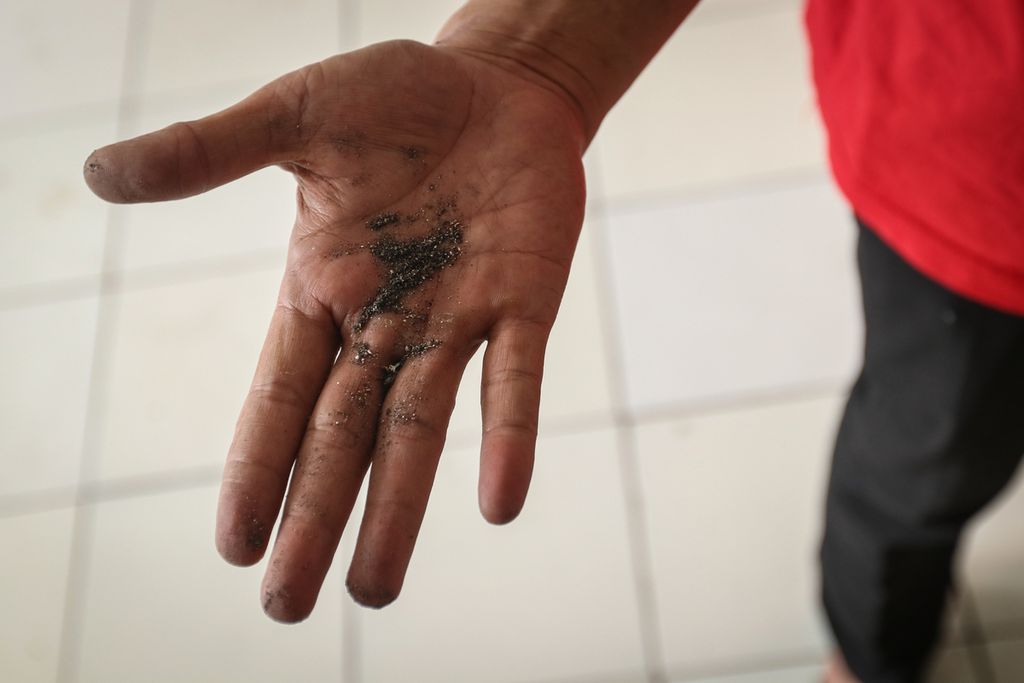 Seorang warga menunjukkan debu hitam di Rusunawa Marunda, Cilincing, Jakarta Utara, Rabu (29/3/2023). 