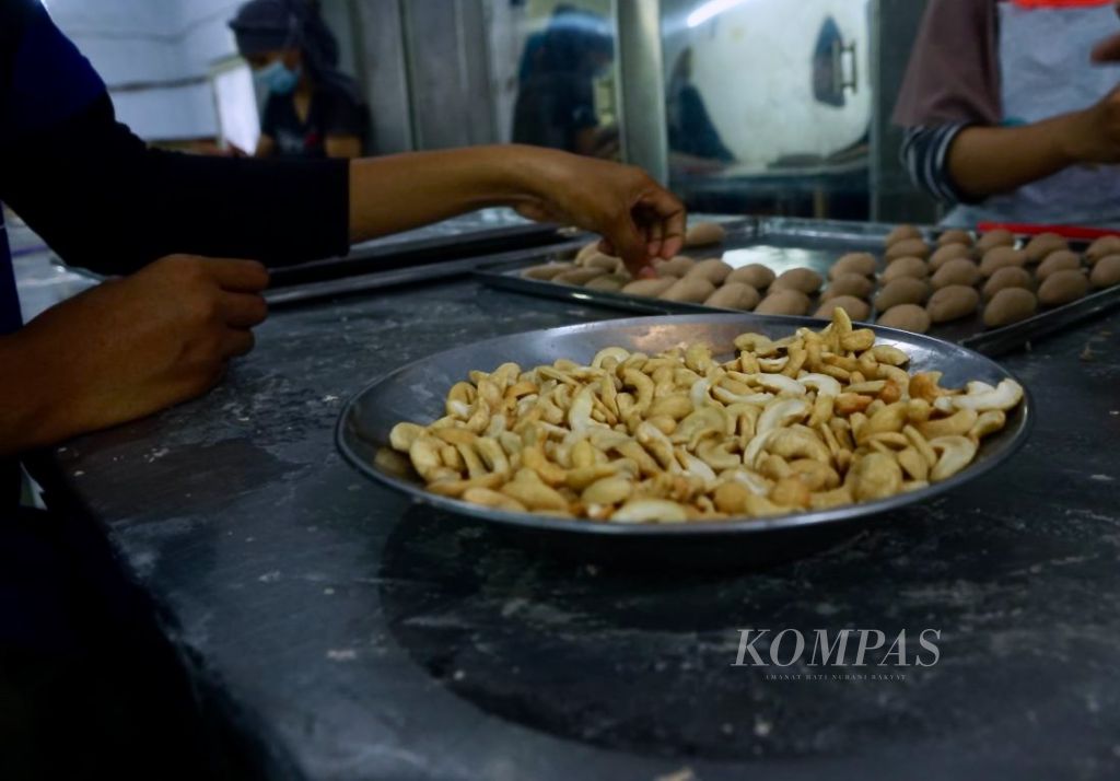 Karyawan toko oleh-oleh Bravo mengolah mete untuk ditaburkan pada kue khas daerah, di Kendari, Sulawesi Tenggara, Minggu (23/7/2023). Mete dan berbagai bentuk olahannya menjadi pilihan utama masyarakat saat berkunjung ke wilayah ini.