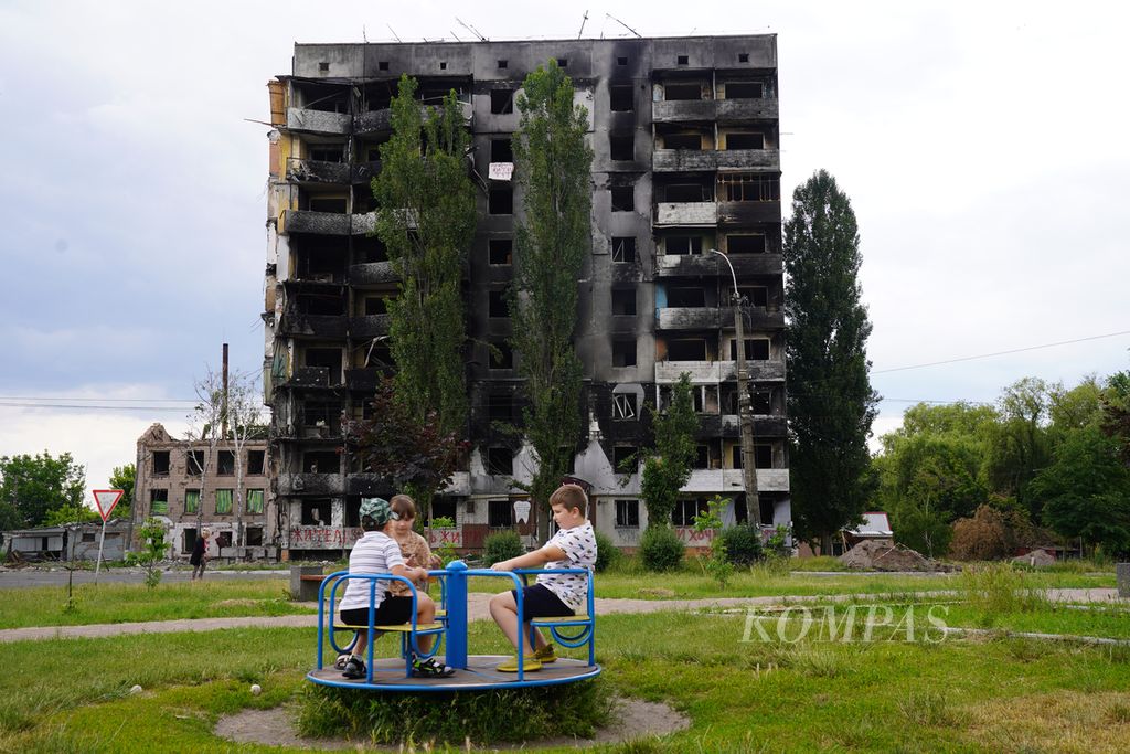 Anak-anak bermain di lapangan seberang sebuah apartemen yang hancur dihantam rudal Rusia di Borodyanka, Provinsi Kyiv, Ukraina, Jumat (17/6/2022). 