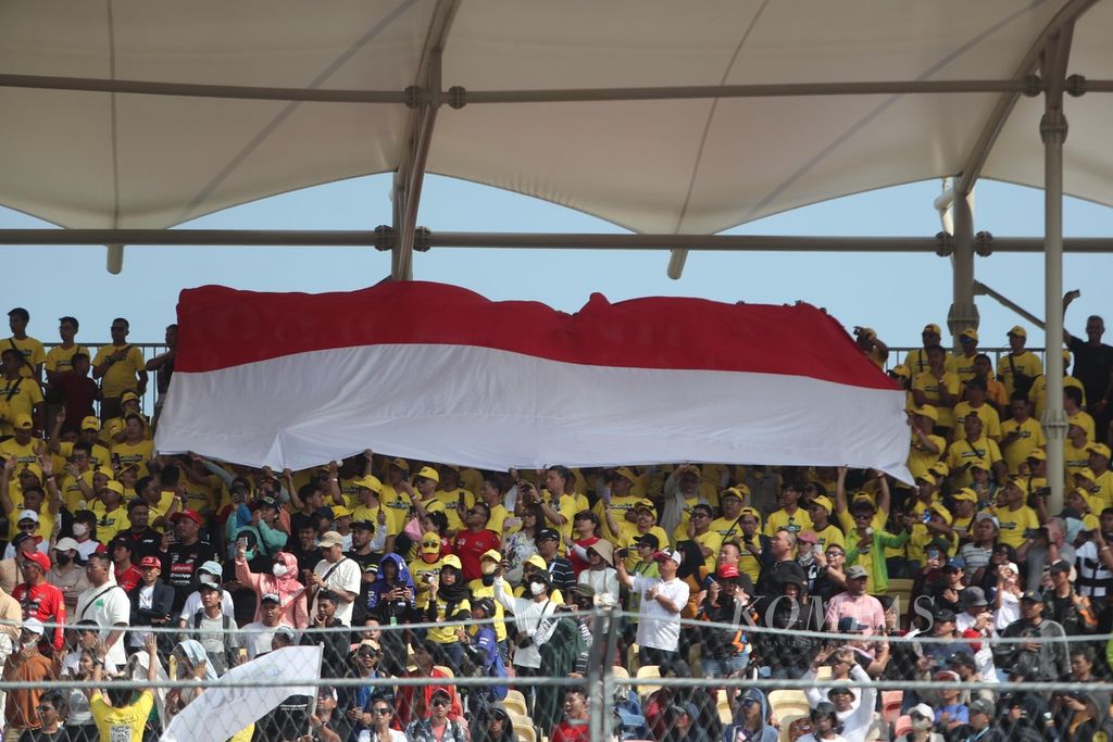Bendera Merah Putih dibentangkan penonton di tribune saat balapan MotoGP seri Indonesia di Sirkuit Internasional Pertamina Mandalika, Lombok Tengah, NTB, Minggu (15/10/2023). Luapan penonton membuat harga hotel dan sewa kendaraan melonjak berlipat-lipat.