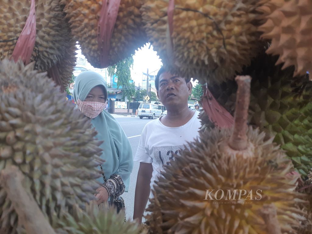 Pedagang durian di Kawasan Demang Lebar Daun Palembang, Aidi (34) (kanan), melayani seorang pembeli, Rabu (4/5/2022). Durian menjadi salah satu buah kegemaran warga Palembang dan pendatang. Ribuan durian ludes disantap setiap hari di Palembang.