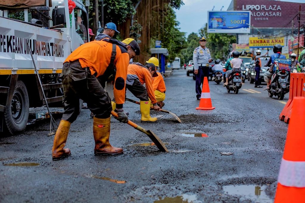 Petugas memperbaiki Jalan Raya Tajur, Kota Bogor, Jabar, yang rusak, Selasa (3/1/2022). 