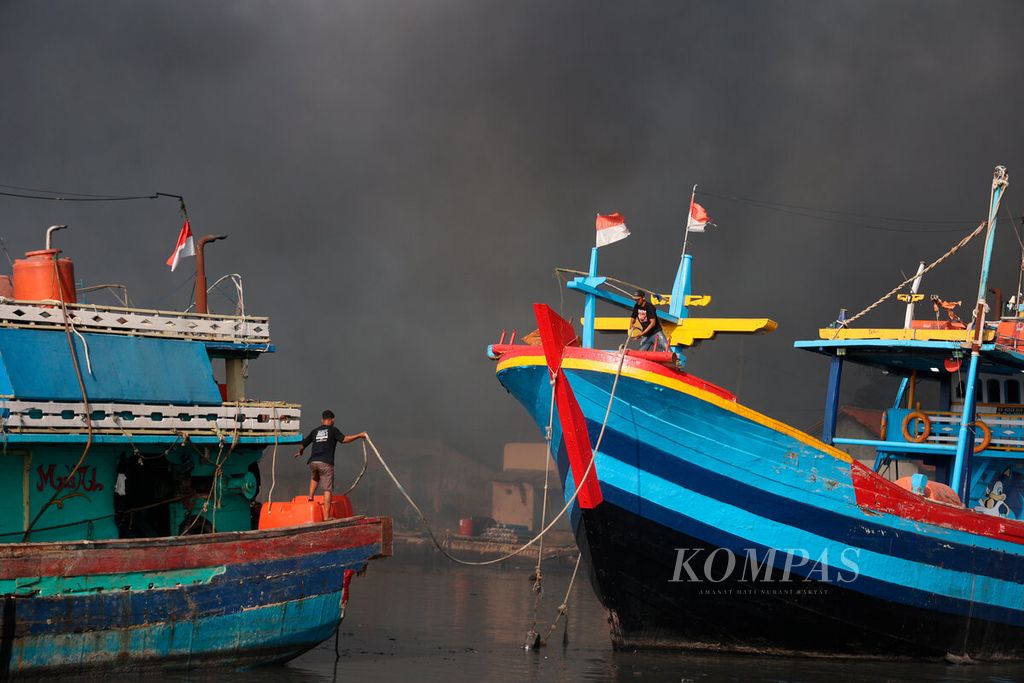 Awak kapal nelayan memindahkan armadanya ke lokasi aman agar terhindar dari bencana kebakaran besar di Pelabuhan Jongor, Kota Tegal, Jawa Tengah, Selasa (15/8/2023). 