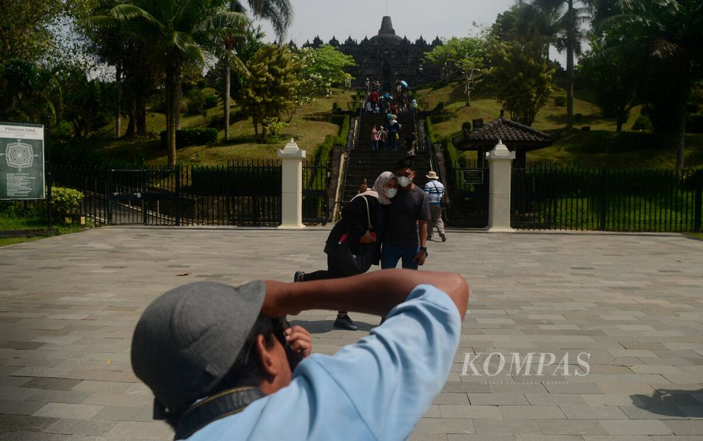Fotografer keliling saat memotret pengunjung yang berwisata di Candi Borobudur, Kabupaten Magelang, Jawa Tengah, Selasa (7/6/2022). Pelonggaran pembatasan sosial kembali menggerakkan usaha kecil di sekitar kawasan Borobudur dalam beberapa bulan ini. 