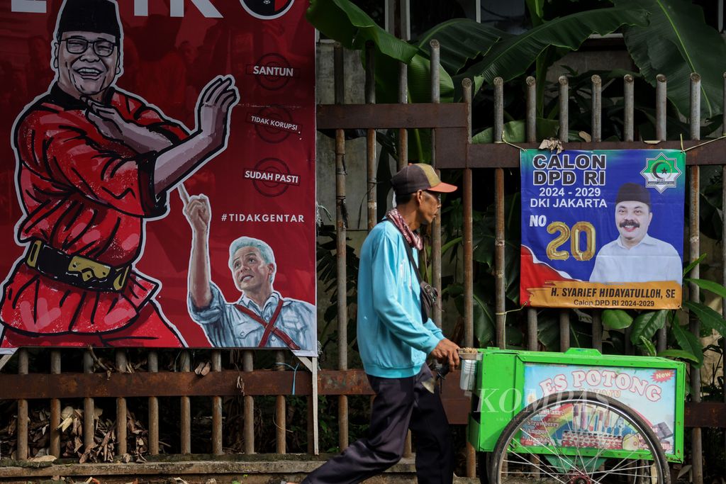 Penjual es potong melintas di depan baliho dan spanduk caleg Pemilu 2024 di Jalan Duren Tiga Selatan, Jakarta Selatan (5/12/2023). 