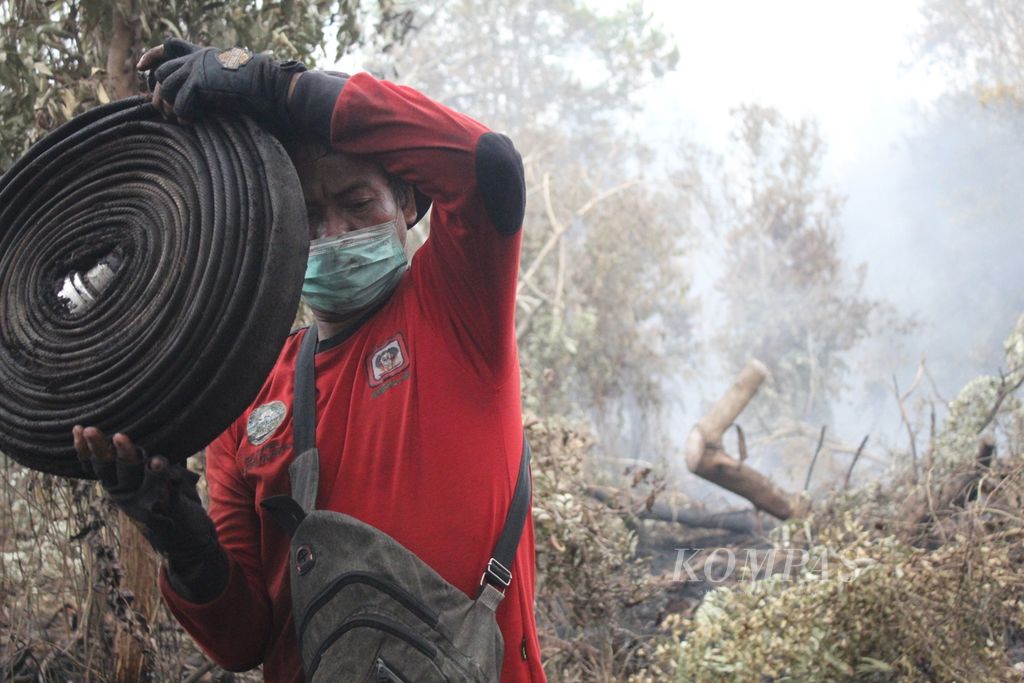 Petugas dari Manggala Agni Kalimantan Tengah menggulung selang sebelum pulang dari lokasi yang masih terbakar di Desa Tumbang Nusa, Kabupaten Pulang Pisau, Kalimantan Tengah, Selasa (3/10/2023). 